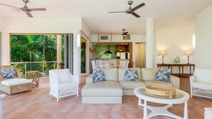 A spacious living area with a sofa set, a round glass table, and a balcony with a view of lush greenery. - The Hill Villa 2 Port Douglas (Port Douglas)