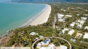 An aerial view of a coastal area with a beach, dense vegetation, and several buildings. - The Hill Villa 2 Port Douglas (Port Douglas)