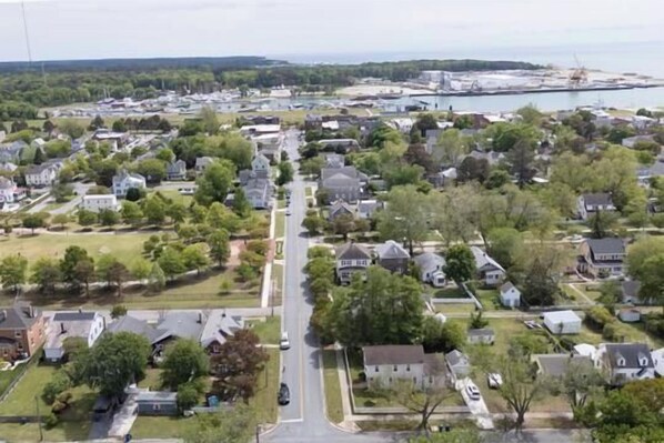 A residential area with houses, a central road, and a body of water in the background.