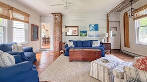 A spacious living room with a blue sofa, a wooden coffee table, and a striped ottoman. - GOOD VIBES IS WHAT YOU'LL FEEL WHEN YOU STEP IN TO OUR FAMILY FRIENDLY LISTING (Cape Charles)