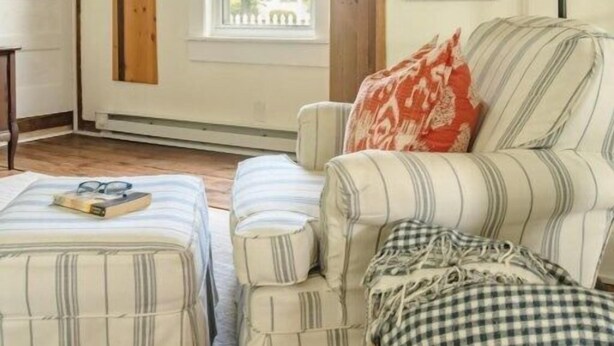 A cozy room with a striped sofa, ottoman, and a window with a view. - GOOD VIBES IS WHAT YOU'LL FEEL WHEN YOU STEP IN TO OUR FAMILY FRIENDLY LISTING (Cape Charles)