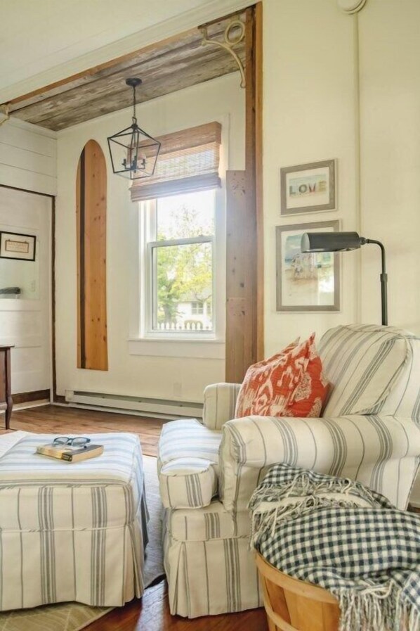 A cozy room with a striped sofa, ottoman, and a window with a view.