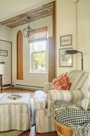 A cozy room with a striped sofa, ottoman, and a window with a view.