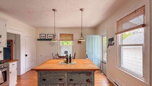 A kitchen with a wooden island, pendant lights, a blue door, and a window with blinds. - GOOD VIBES IS WHAT YOU'LL FEEL WHEN YOU STEP IN TO OUR FAMILY FRIENDLY LISTING (Cape Charles)