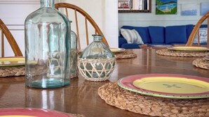 A dining table with glass bottles, woven placemats, and colorful plates. - GOOD VIBES IS WHAT YOU'LL FEEL WHEN YOU STEP IN TO OUR FAMILY FRIENDLY LISTING (Cape Charles)