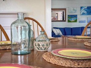 A dining table with glass bottles, woven placemats, and colorful plates.