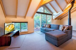 A modern living room with a large window, a sofa, a TV, and a fireplace.