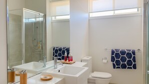 Un baño moderno con dos lavabos, ducha e inodoro.