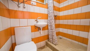 A bathroom with a white toilet, a sink, and a shower with a curtain. - Smart Apartment Zamarstinivska 20a (Lviv)