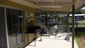 An outdoor patio with a grill, tables, and chairs. - Palmgrove 1 - Rainbow Beach. Gorgeous, modern beach escape in a great location. Aircon. Wifi (RAINBOW BEACH)
