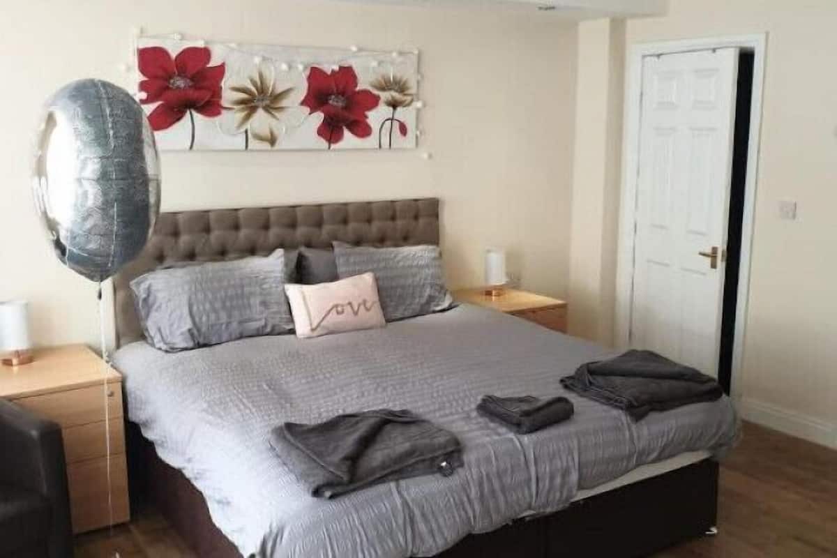 Une chambre à coucher avec un grand lit, une table de chevet, une commode et une œuvre d’art accrochée au mur.