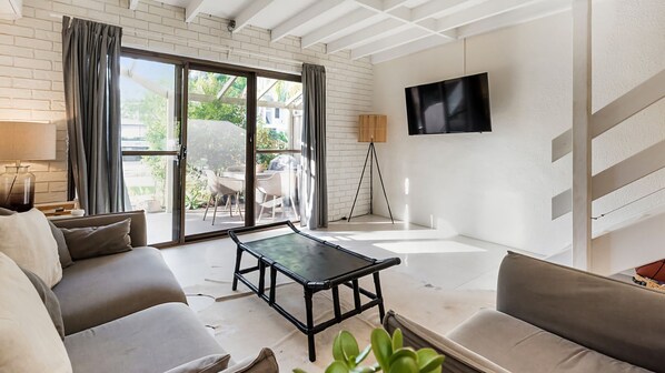 Ein modernes Wohnzimmer mit einer Couch, einem Couchtisch und einem an der Wand montierten Fernseher.