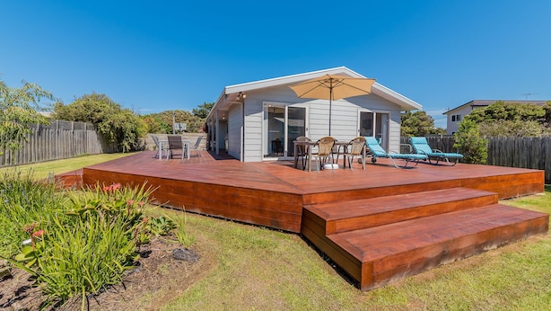 Une maison moderne dotée d’une terrasse, d’un espace salon extérieur et d’un grand parasol.