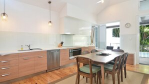 Eine moderne Küche mit Holzausstattung, Edelstahlgeräten und einem Essbereich mit Holztisch und Stühlen.