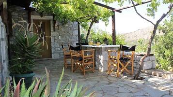 An outdoor patio with stone flooring, wooden chairs, and a table.