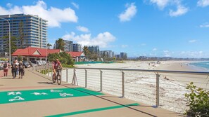 A coastal walkway with a bike lane, beach, and high-rise buildings in the background. - Grande Corniche U17 - Panoramic Kirra Hill (Kirra)