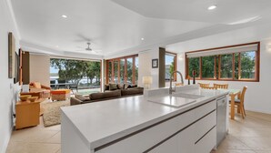 A modern kitchen with a central island, large windows, and a view of the outdoors.