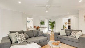 Ein modernes Wohnzimmer mit zwei grauen Sofas, einem Couchtisch und einem Deckenventilator.