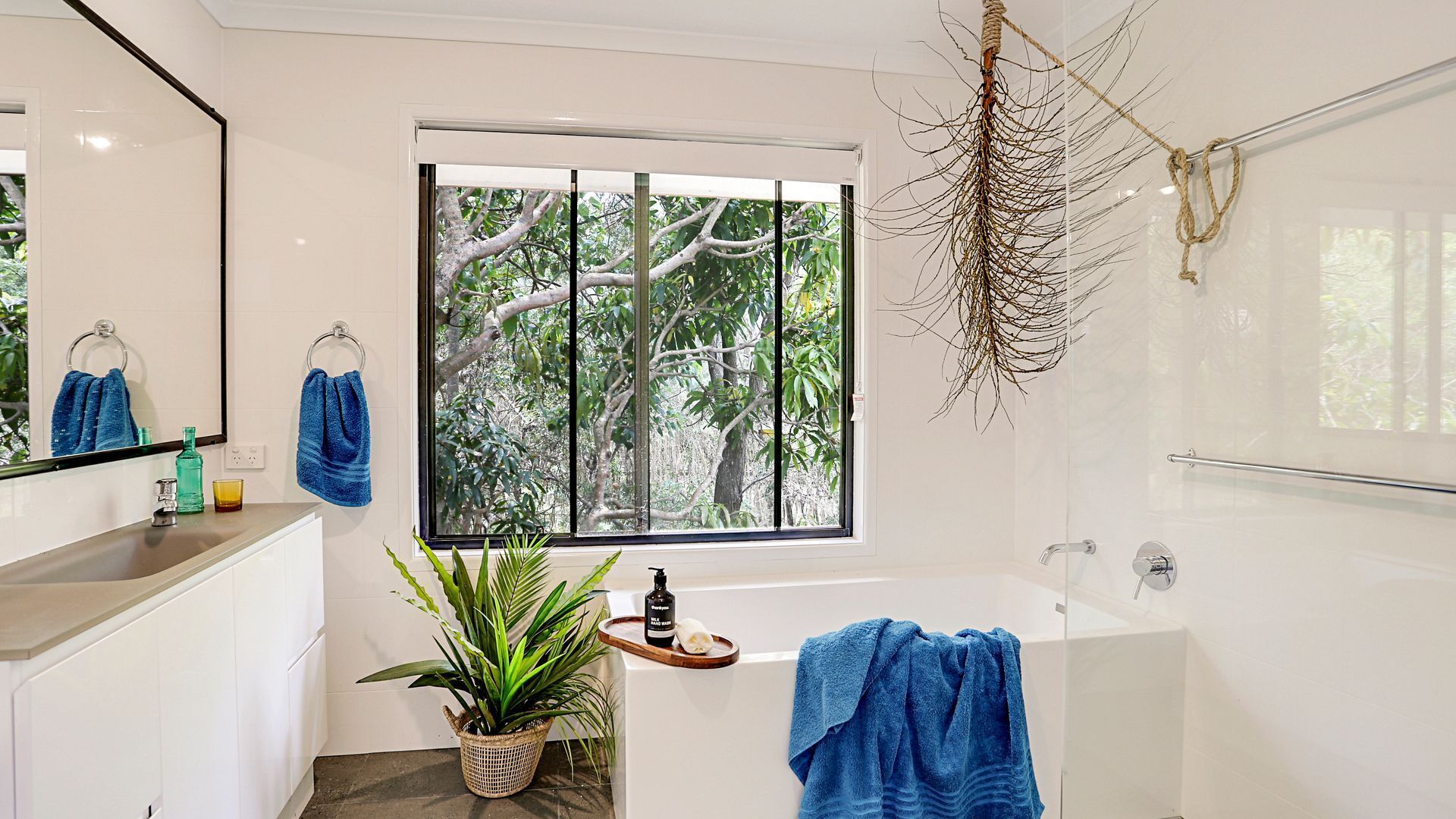 A modern bathroom with a bathtub, a sink, and a window with a view of trees.