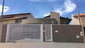 A gated residential area with a modern house featuring a curved roof and a grey facade. - Recanto da Bia, 3 bedrooms, air conditioning, Wi-Fi and 4 minutes from the park. (Olímpia)