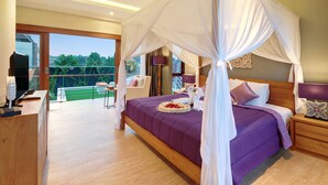 Un dormitorio con una cama grande, televisión y un balcón con vistas a zonas verdes.