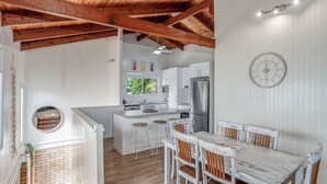 Een moderne keuken met witte kasten, een centraal eiland en een eethoek met houten stoelen.