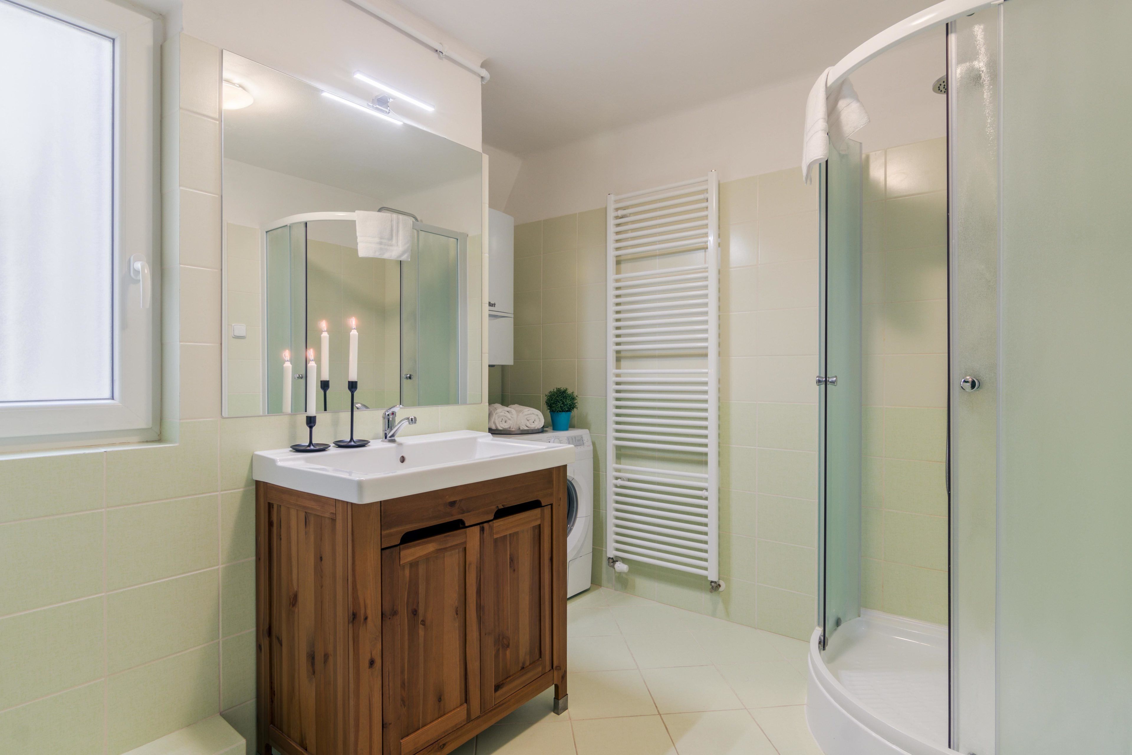 Un baño con tocador de madera, un espejo, un lavabo, un perchero para toallas y una ducha con mampara de cristal.