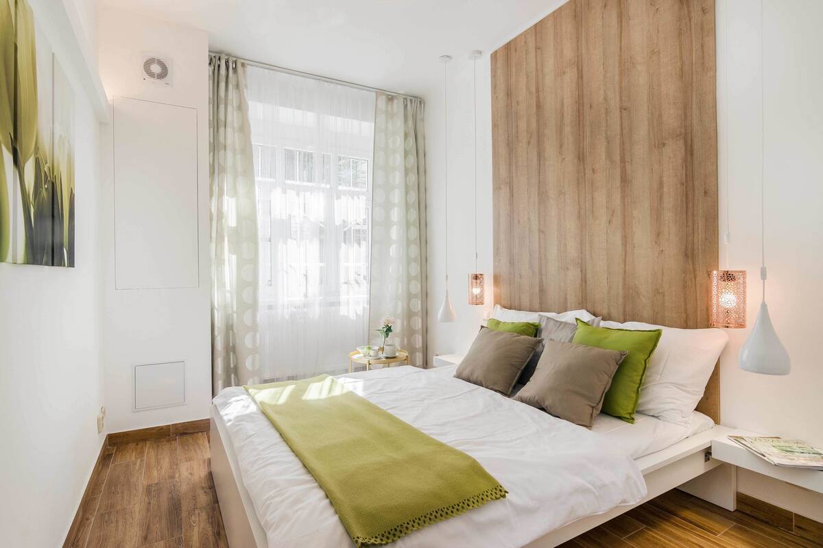 Een slaapkamer met een groot bed, een houten hoofdbord en een nachtkastje met een lamp.