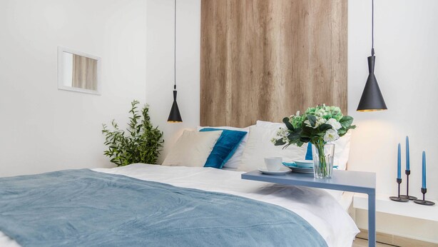 Ein modernes Schlafzimmer mit einem großen Bett, einem Nachttisch mit Blumenvase und einem Holzkopfende.