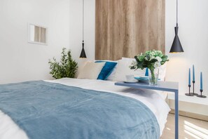 Une chambre à coucher moderne avec un grand lit, une table de chevet ornée d’un vase de fleurs et une tête de lit en bois.