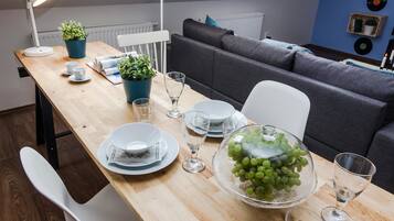 A dining area with a wooden table set for four, a grey sofa, and a blue wall with vinyl records.