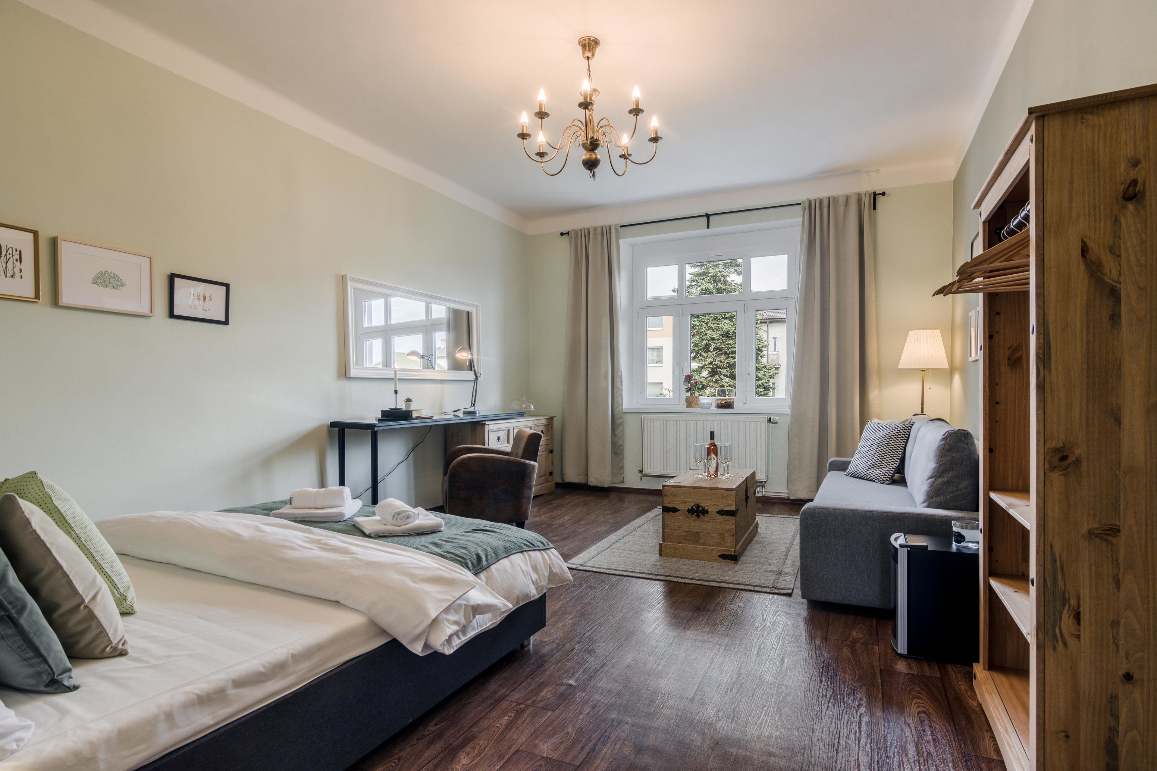 Un dormitorio bien iluminado con cama, escritorio, silla, sofá y armario.