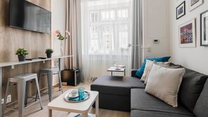 Ein modernes Wohnzimmer mit Flachbildfernseher, einer Couch, einem Couchtisch und einem Essbereich mit Barhocker.