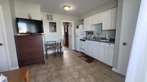 Kitchen area with flat-screen TV, microwave, stove, and dining table.