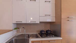 Une cuisine avec des armoires blanches, un évier en acier inoxydable et une cuisinière à gaz.