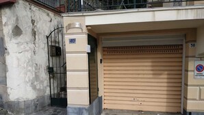 Un bâtiment avec une porte de garage fermée, un portail en métal et un panneau indiquant qu’il est interdit de se garer.