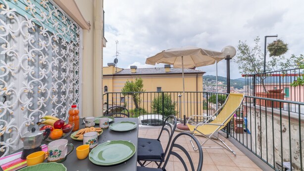 Un balcon avec une table préparée pour le petit-déjeuner, une chaise et un parasol.
