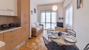 Une cuisine compacte équipée d’une cuisinière, de placards et d’un coin repas avec une table dressée pour deux personnes.