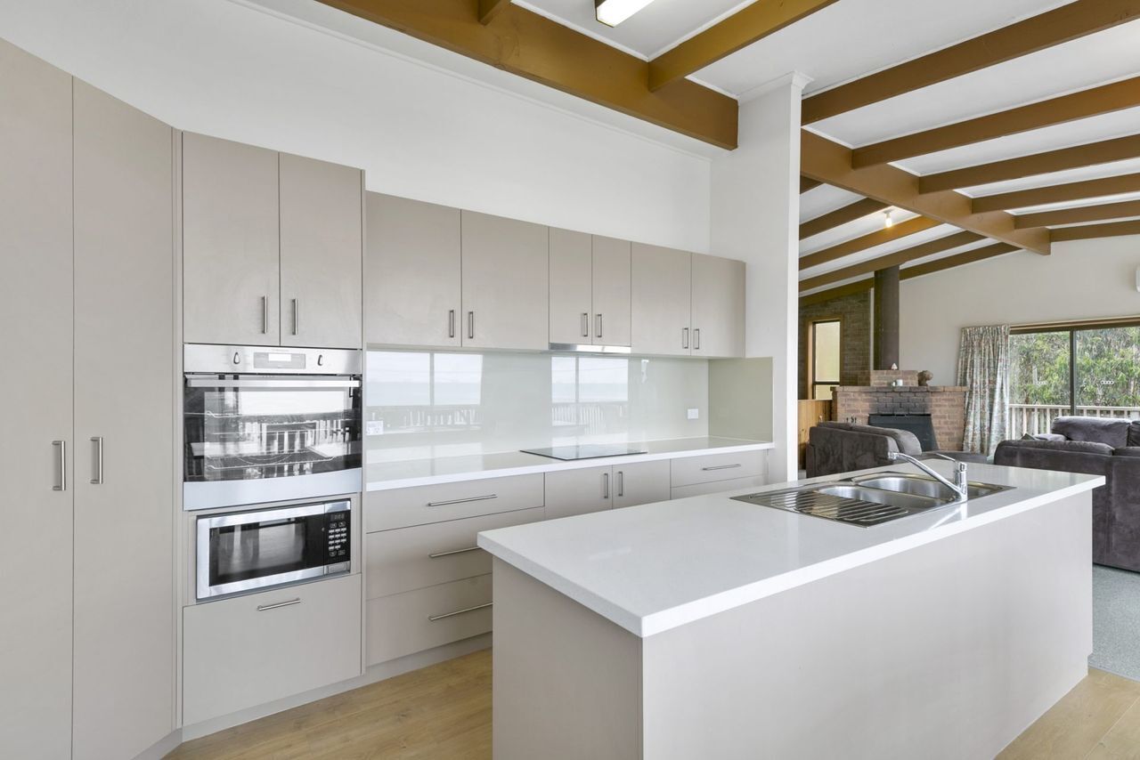 A modern kitchen with white cabinetry, stainless steel appliances, and a large island with a sink.