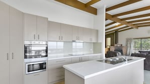 A modern kitchen with white cabinetry, stainless steel appliances, and a large island with a sink.