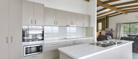 A modern kitchen with white cabinetry, stainless steel appliances, and a large island with a sink.