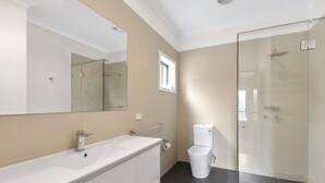 A modern bathroom with a glass shower enclosure, a white sink with a mirror, and a toilet.