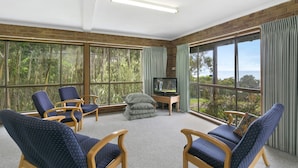 A room with large windows, a television, and several chairs.