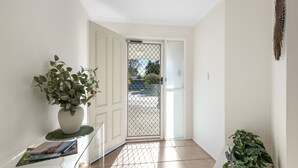 Un passadís amb una porta blanca, una planta en test i un sòl emblat.