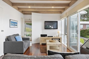 A modern living room with a sofa, a coffee table, and a television on a wall. - On The Deck (Lorne)