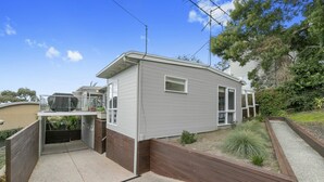 A single-story house with a covered patio, a small garden area, and a visible satellite dish. - On The Deck (Lorne)