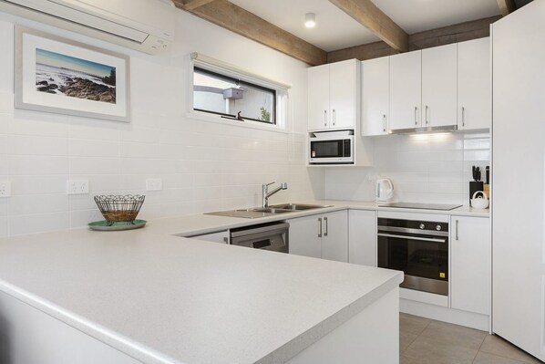 A modern kitchen with white cabinetry, a built-in microwave, and a stainless steel oven.