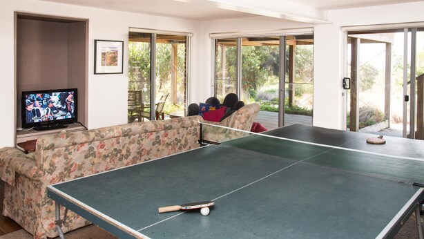 Una sala de estar con mesa de ping pong, televisión y sofá.