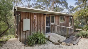 A wooden cabin with a deck, a door, and a sign indicating a beach shack.