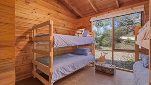 A wooden cabin with bunk beds, a small window, and a suitcase on the floor.